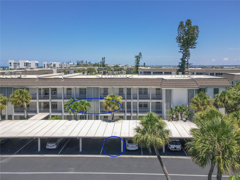 An exterior view of a multi-story apartment building with a covered parking area in front — 4340 FALMOUTH DRIVE UNIT D-204, LONGBOAT KEY, FL
