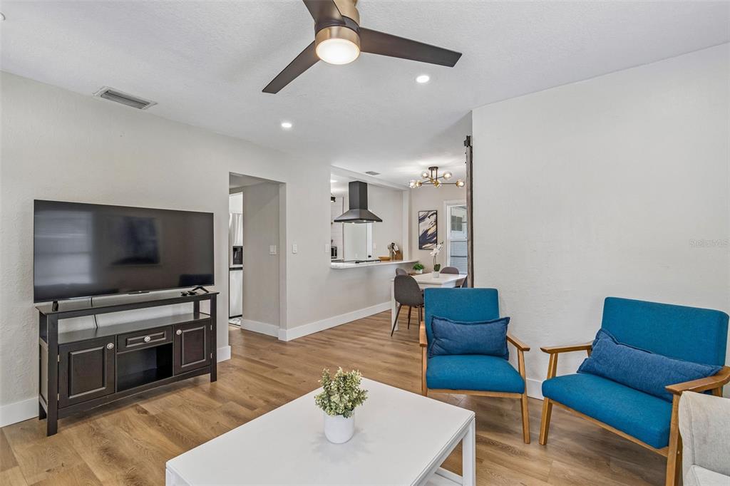 A living room with wood flooring, two blue chairs, a television, and an open kitchen — 4012 N BOULEVARD, TAMPA, FL