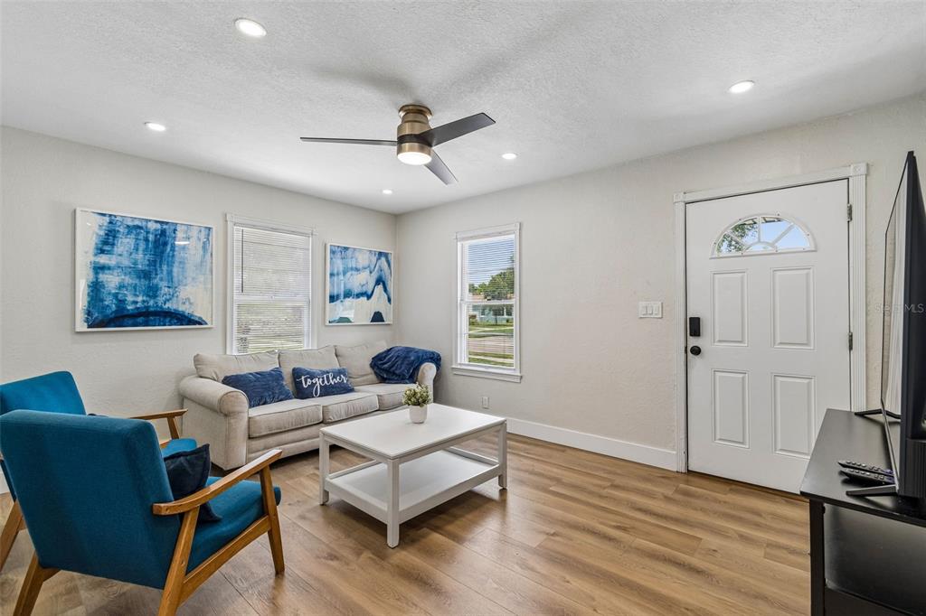 A living room features a sofa, blue armchairs, a coffee table, and wood-look flooring — 4012 N BOULEVARD, TAMPA, FL