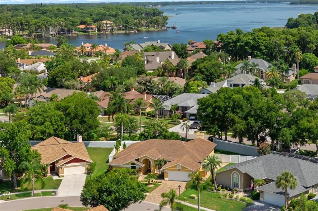 An aerial view of a suburban neighborhood with houses, lush trees, and a large lake — 1874 STABLE TRAIL, PALM HARBOR, FL