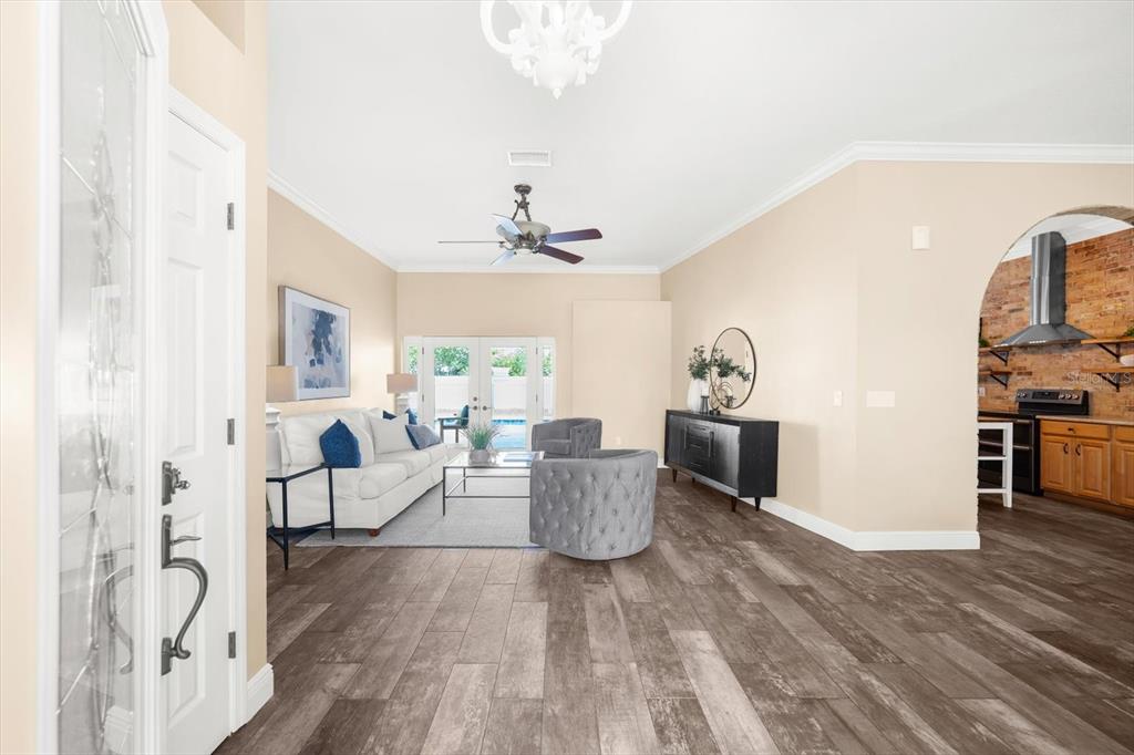 A living room with wood-look flooring, a white sofa, and an arched kitchen entrance — 1874 STABLE TRAIL, PALM HARBOR, FL