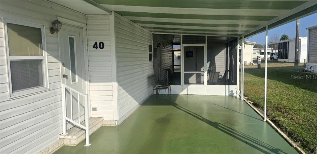 A mobile home exterior features a green concrete porch, a screened-in area, and white siding — 40 CONCORD LANE, PALM HARBOR, FL