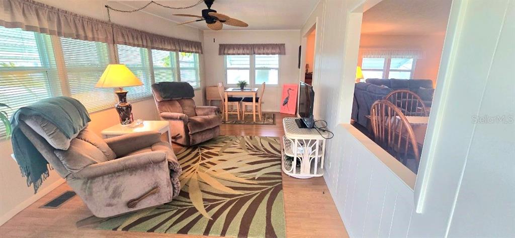 A sunroom features a recliner, a dining set, and a large patterned area rug — 40 CONCORD LANE, PALM HARBOR, FL