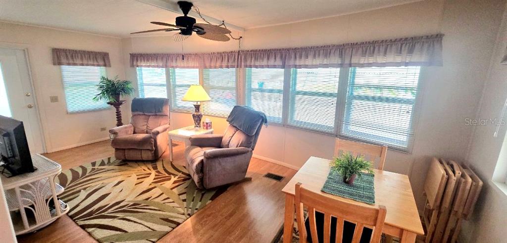 A sunroom features two recliners, a small dining table, and large windows with horizontal blinds — 40 CONCORD LANE, PALM HARBOR, FL