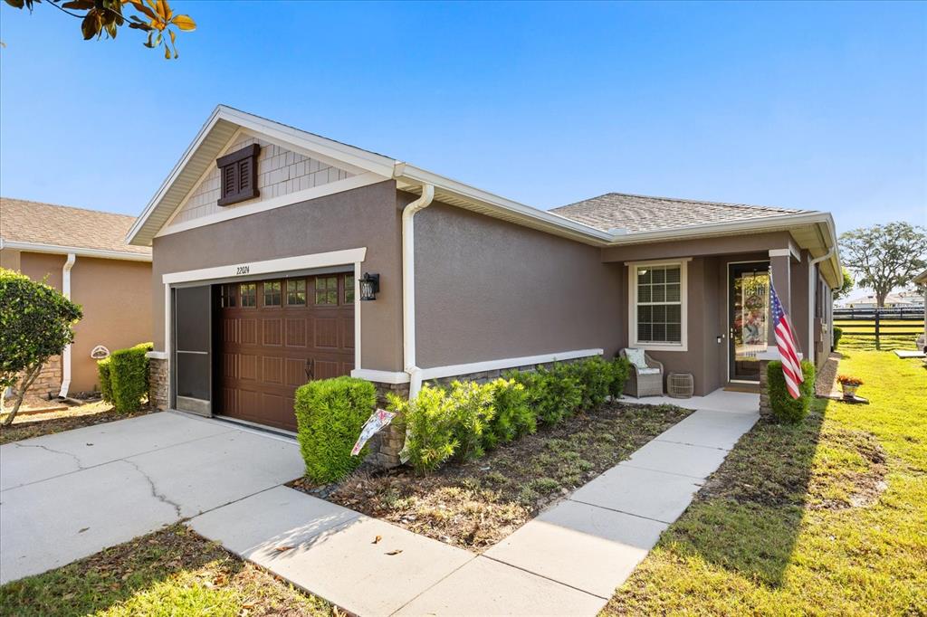 A kitchen features wood cabinets, black appliances, tile flooring, and a breakfast bar — 22024 BELGIAN COURT, MOUNT DORA, FL