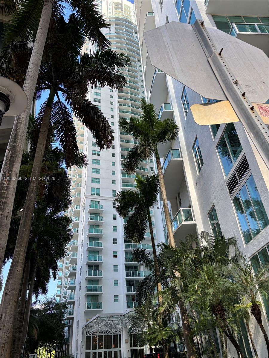 A low-angle view of a tall white residential high-rise building surrounded by palm trees — 31 SE 5th St # 2103, Miami FL 33131, MIAMI, FL