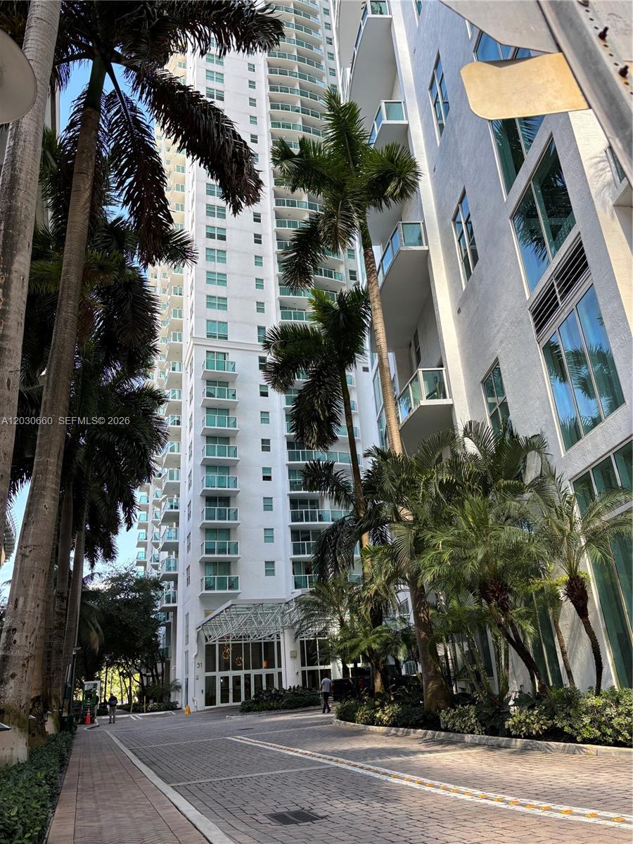 A tall white residential high-rise building stands surrounded by palm trees and a paved driveway — 31 SE 5th St # 2103, Miami FL 33131, MIAMI, FL