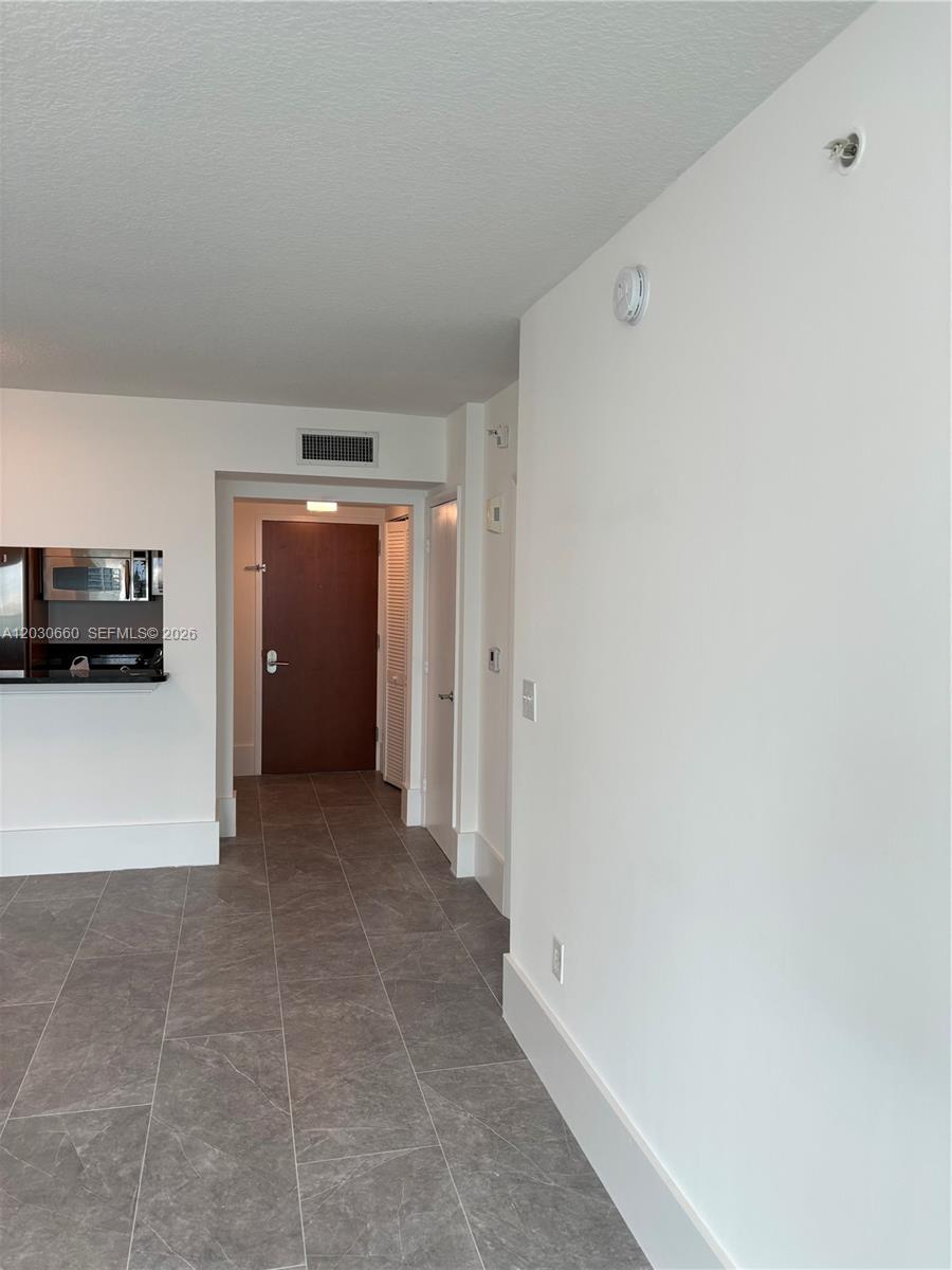A tiled hallway leads to a dark wood entrance door next to a kitchen area — 31 SE 5th St # 2103, Miami FL 33131, MIAMI, FL