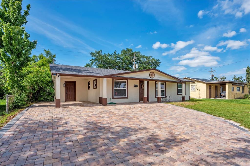 A single-story house with a paved driveway, a covered carport, and a light-colored exterior — 4325 CASSIUS STREET, ORLANDO, FL