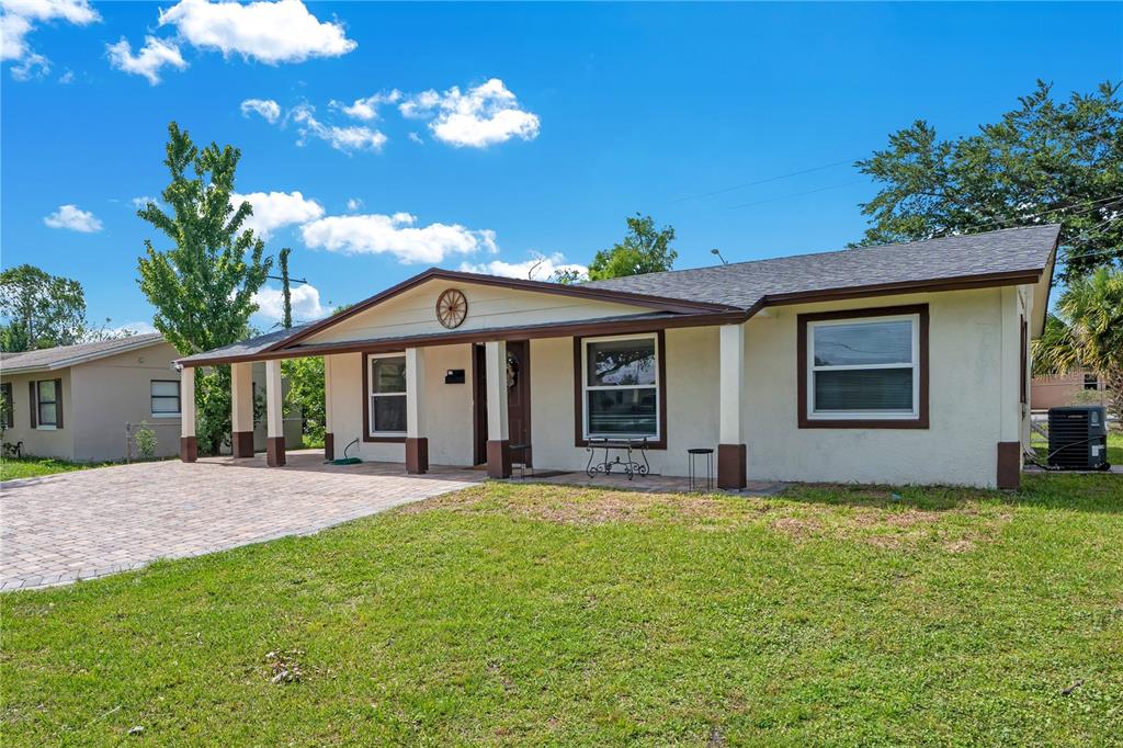 A single-story house with a paved driveway, covered front porch, and a grassy lawn — 4325 CASSIUS STREET, ORLANDO, FL