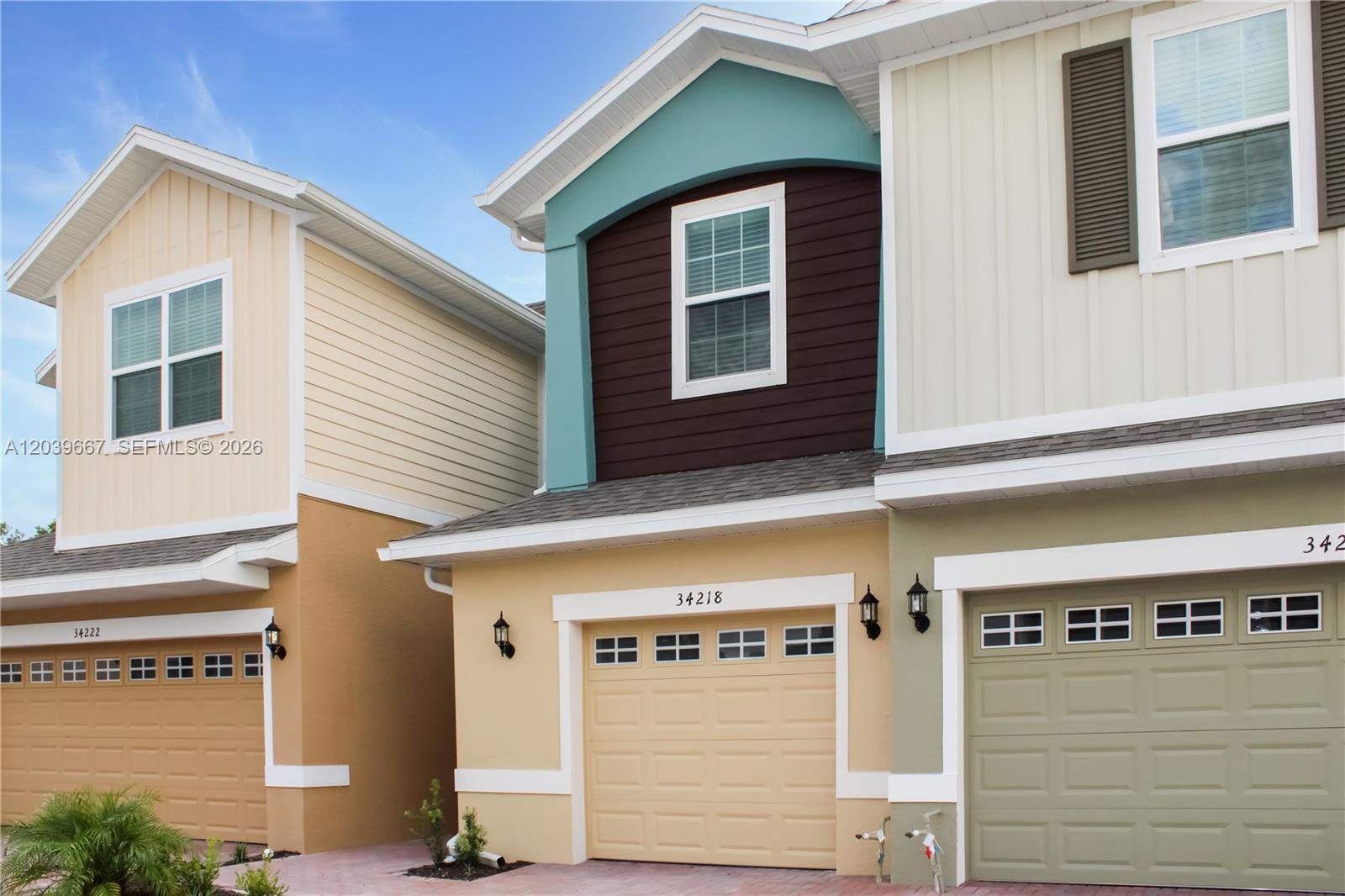 The exterior of three adjacent townhomes features varied siding colors, garage doors, and gabled roofs — 34218 Cinder Way # 34218, Zephyrhills FL 33545, ZEPHYRHILLS, FL