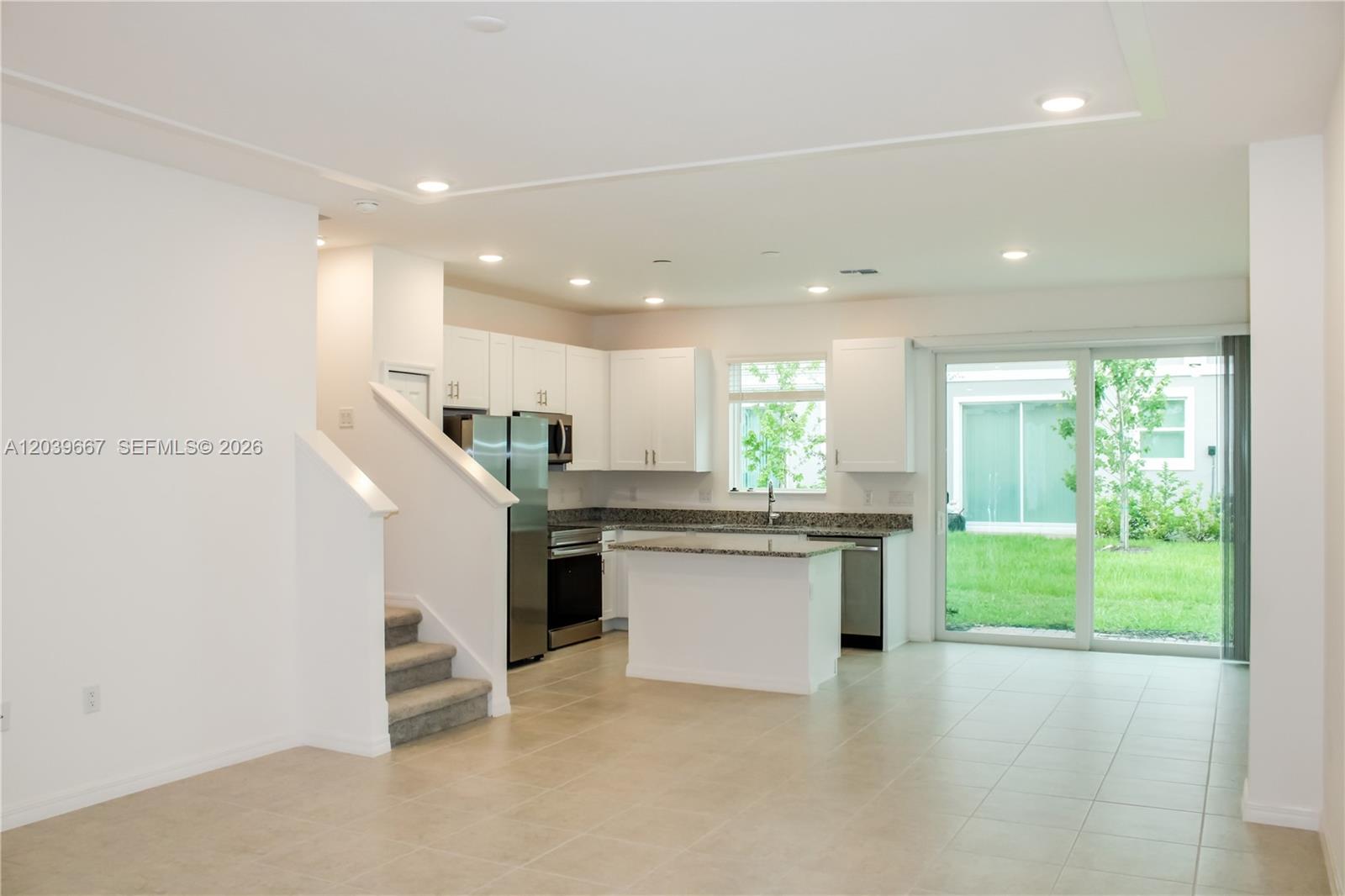 A kitchen with white cabinets, granite countertops, and stainless steel appliances overlooks a backyard — 34218 Cinder Way # 34218, Zephyrhills FL 33545, ZEPHYRHILLS, FL