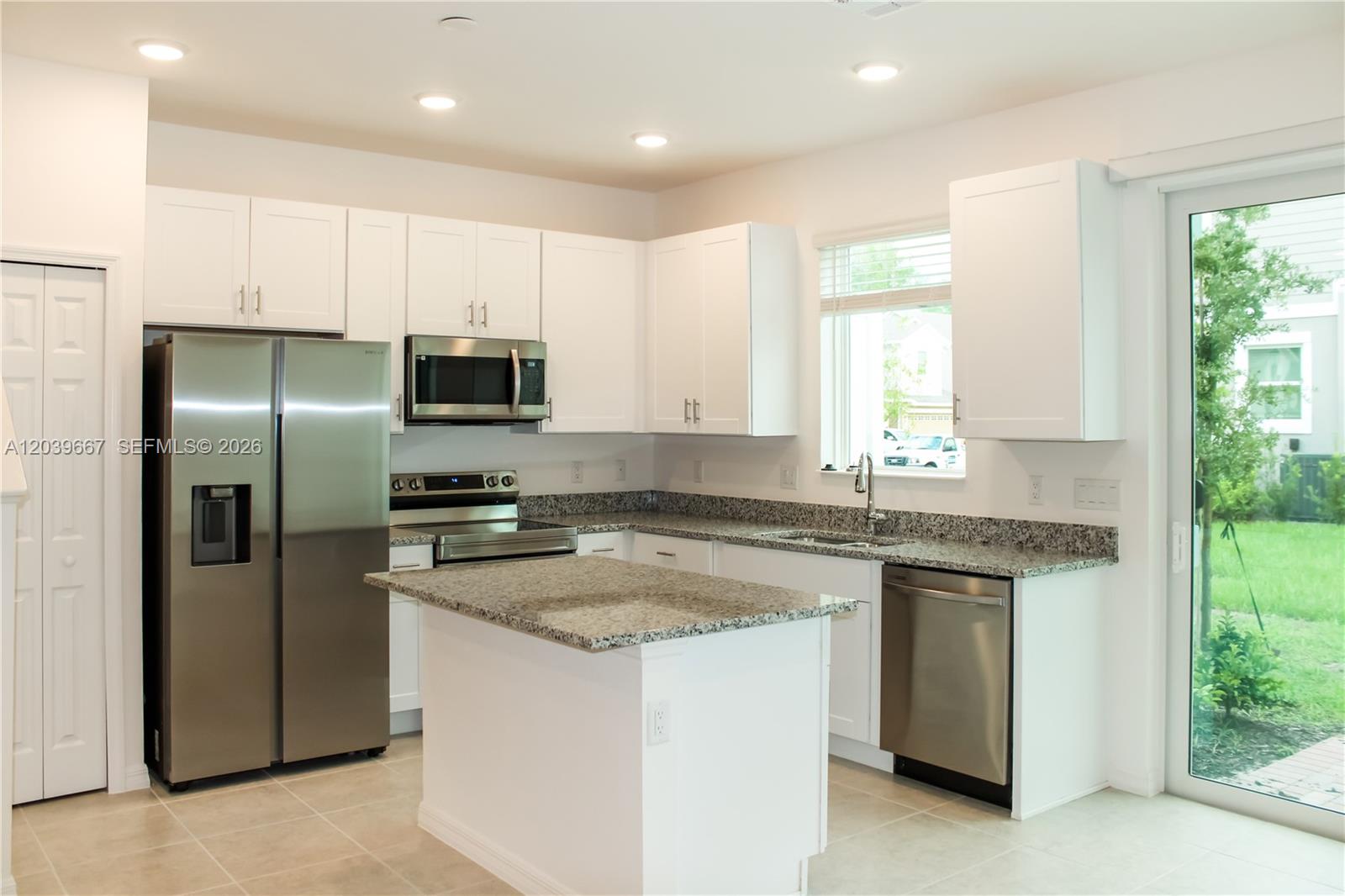 A kitchen features white cabinetry, granite countertops, stainless steel appliances, and a central island — 34218 Cinder Way # 34218, Zephyrhills FL 33545, ZEPHYRHILLS, FL