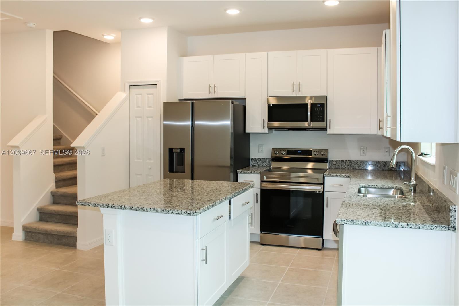 A modern kitchen features white cabinets, granite countertops, stainless steel appliances, and an island — 34218 Cinder Way # 34218, Zephyrhills FL 33545, ZEPHYRHILLS, FL