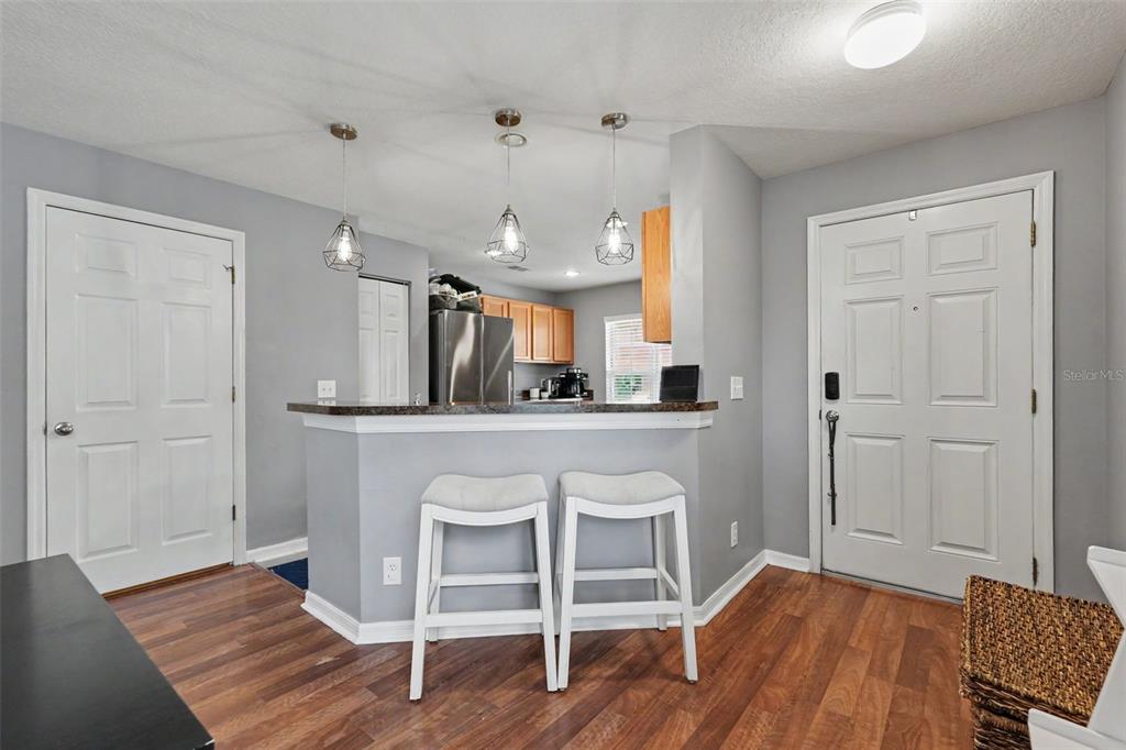A kitchen with a breakfast bar, two stools, and pendant lighting, viewed from an entryway — 1977 SEARAY SHORE DRIVE, CLEARWATER, FL