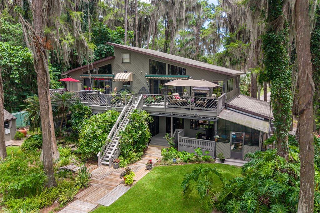 A two-story house with a large wooden deck, outdoor staircase, and surrounding trees — 298 SE 5TH AVENUE, MELROSE, FL