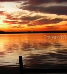 A view of a lake at sunset with a dark wooden dock in the foreground — 298 SE 5TH AVENUE, MELROSE, FL