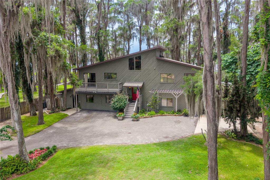 An exterior view of a two-story green house with a shed roof and wooden deck — 298 SE 5TH AVENUE, MELROSE, FL