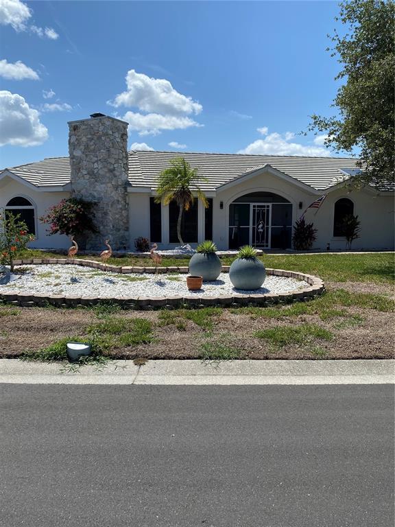 A single-story house with a stone chimney, a landscaped front yard, and a paved driveway — 355 EDEN DRIVE, ENGLEWOOD, FL
