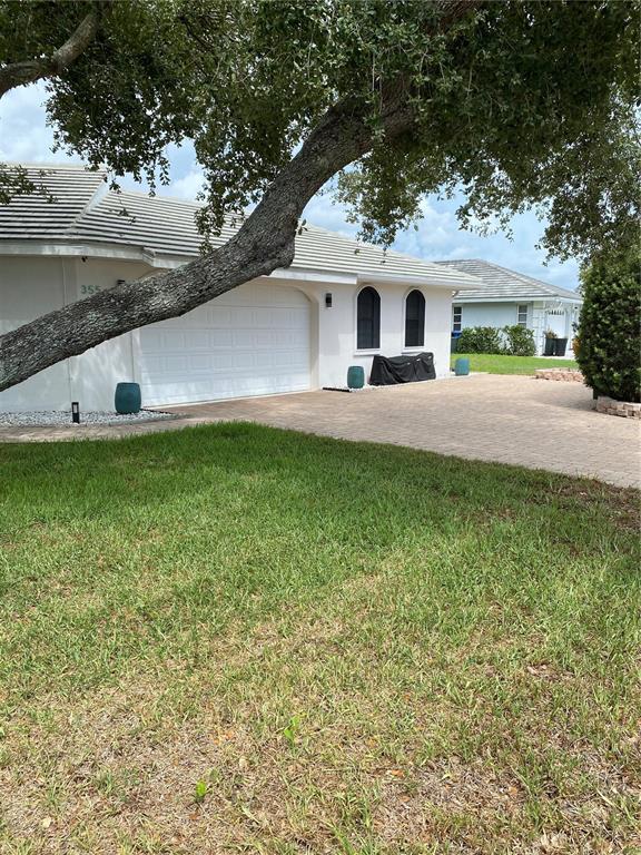 A white house with a two-car garage and a large tree in the front yard — 355 EDEN DRIVE, ENGLEWOOD, FL