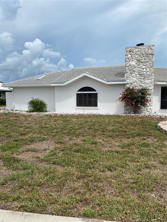 A single-story house with a white exterior, a stone chimney, and a tiled roof — 355 EDEN DRIVE, ENGLEWOOD, FL