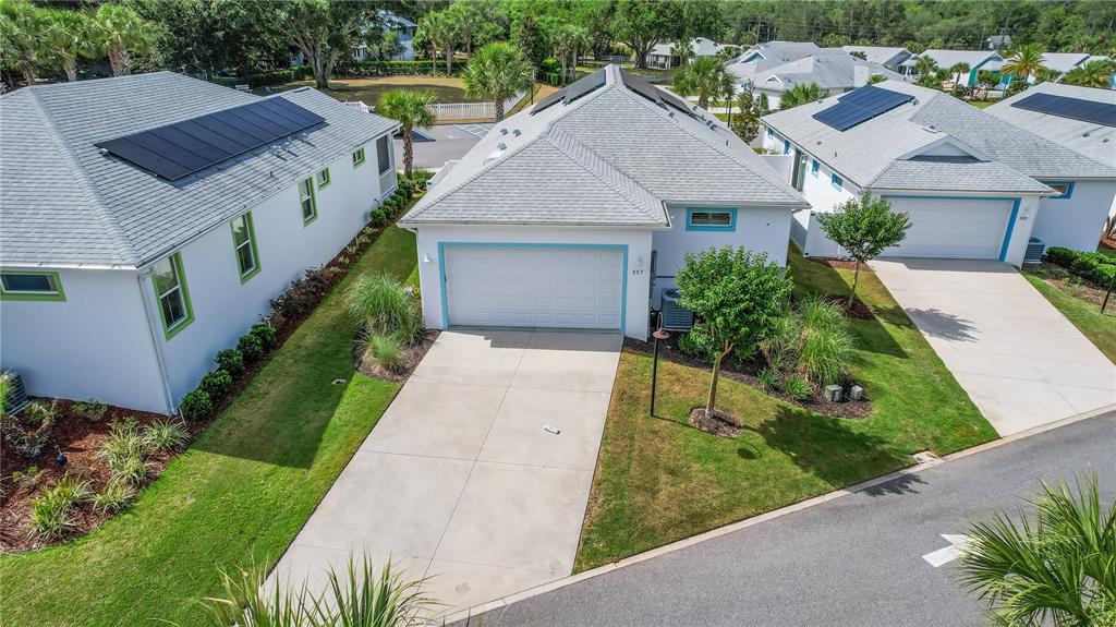 An aerial view shows a suburban house with a white garage and solar roof panels — 357 CONCH KEY LANE, LADY LAKE, FL
