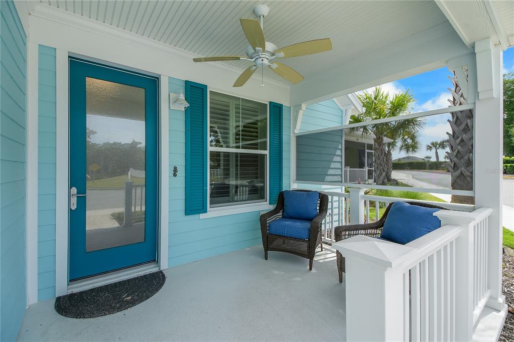 A covered front porch features light blue siding, a teal door, and two wicker chairs — 357 CONCH KEY LANE, LADY LAKE, FL