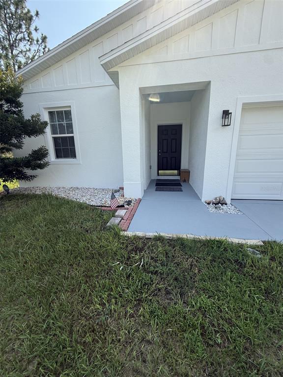 The exterior of a white house features a black front door and a gray walkway — 8565 SW 125TH COURT ROAD, DUNNELLON, FL