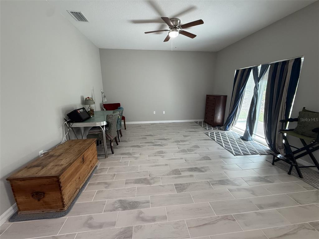 A room with light gray walls, tile flooring, a ceiling fan, and sliding glass doors — 8565 SW 125TH COURT ROAD, DUNNELLON, FL