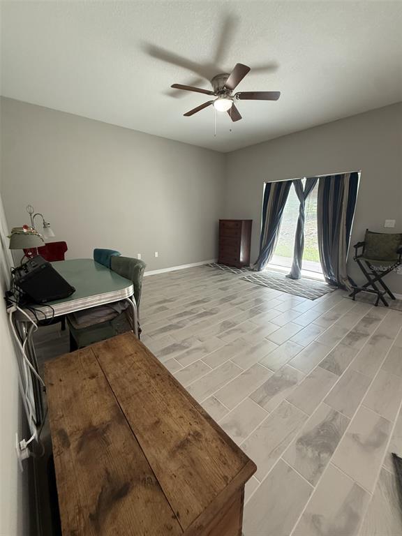 A room with light gray walls, tile flooring, a ceiling fan, and sliding glass doors — 8565 SW 125TH COURT ROAD, DUNNELLON, FL
