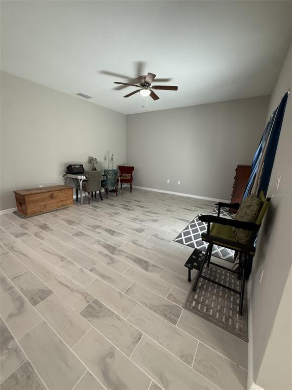 A spacious room features light gray tile flooring, a ceiling fan, and a small dining area — 8565 SW 125TH COURT ROAD, DUNNELLON, FL