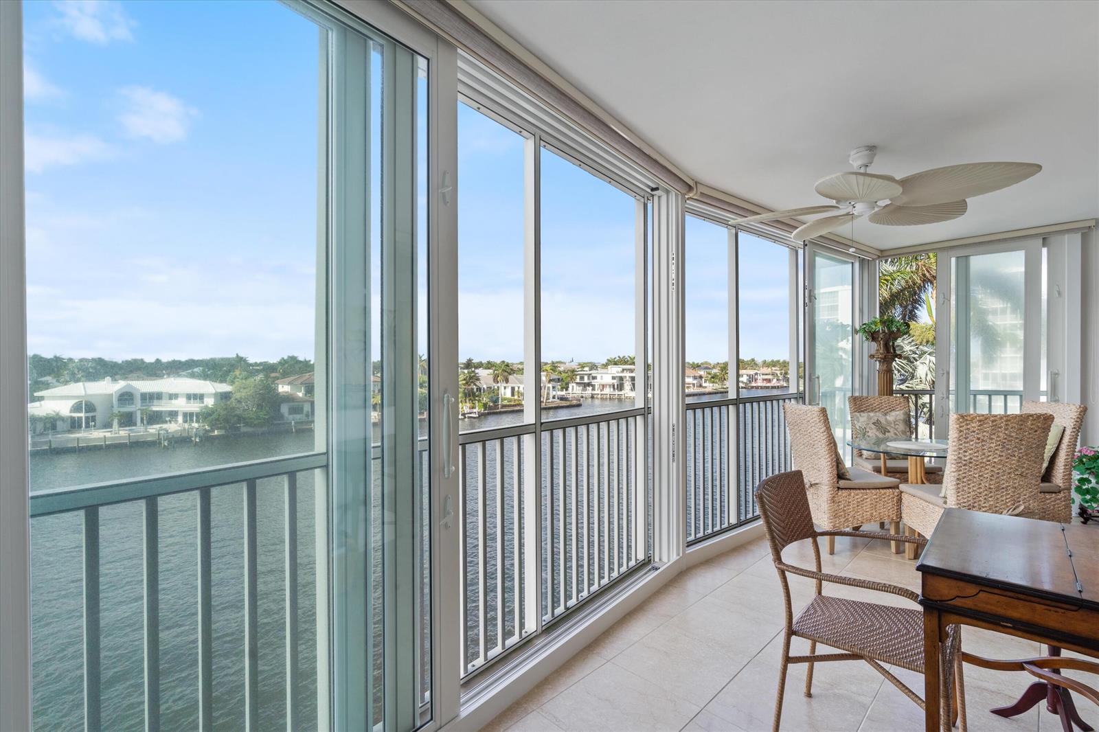 A sunroom with tile flooring, wicker furniture, and sliding glass doors overlooking a waterfront view — 3310 S Ocean Boulevard # d, Highland Beach FL 33487, HIGHLAND BEACH, FL