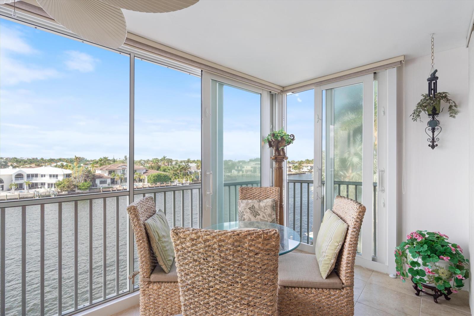 A sunroom with a glass table, wicker chairs, and floor-to-ceiling windows overlooking a waterway — 3310 S Ocean Boulevard # d, Highland Beach FL 33487, HIGHLAND BEACH, FL