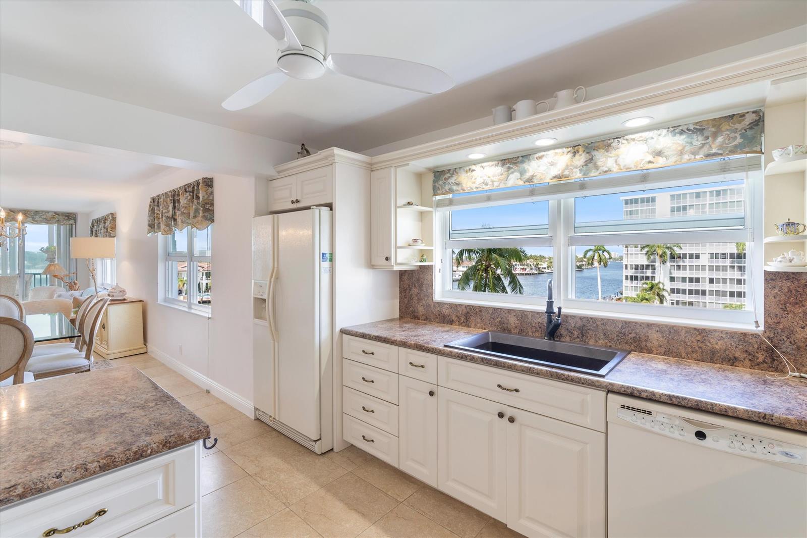 A kitchen with white cabinets, brown countertops, and a sink overlooking a waterfront view — 3310 S Ocean Boulevard # d, Highland Beach FL 33487, HIGHLAND BEACH, FL