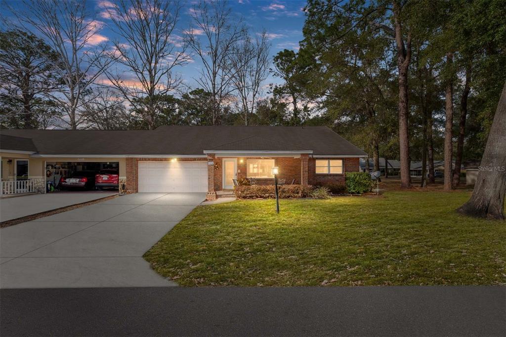 A single-story brick house with a two-car garage and a front lawn at dusk — 8707 SW 88TH COURT ROAD UNIT K, OCALA, FL
