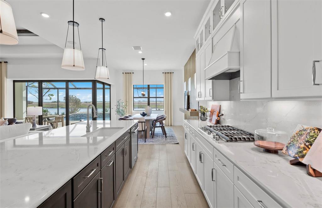 A modern kitchen with white and dark cabinetry, quartz countertops, and a view of a pool — 4933 DEL REY COVE, LAKEWOOD RANCH, FL