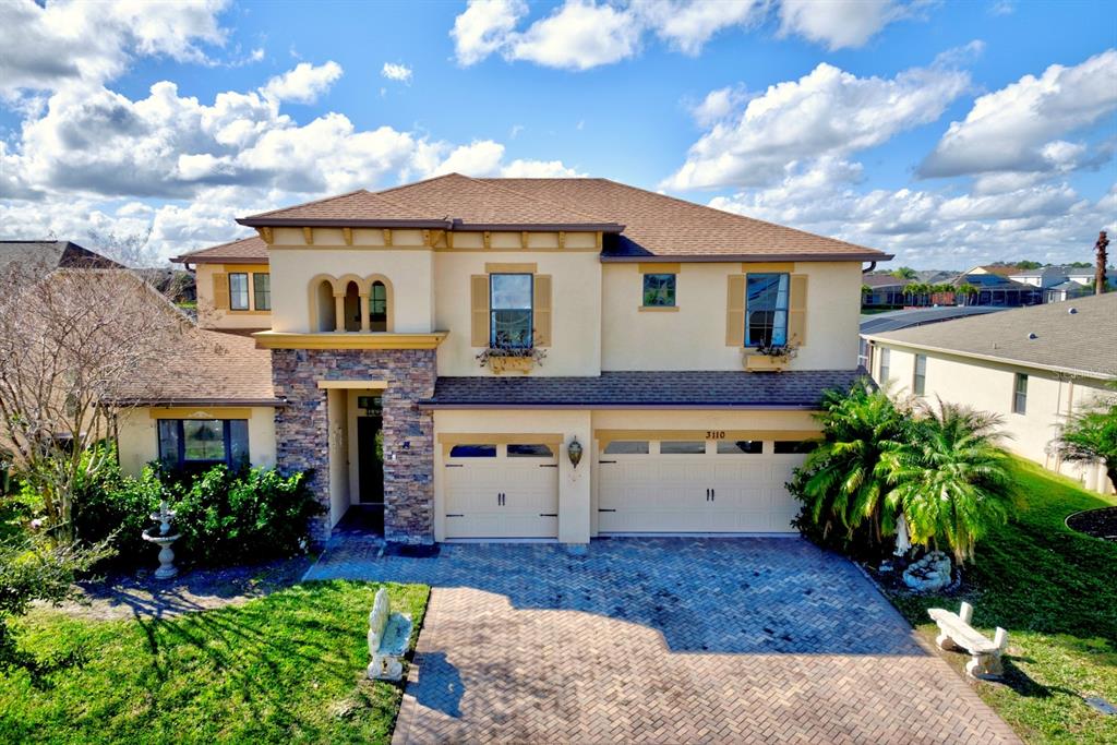A two-story house with a stone facade, beige stucco, and a brick-paved driveway — 3110 BASS BOAT WAY, KISSIMMEE, FL