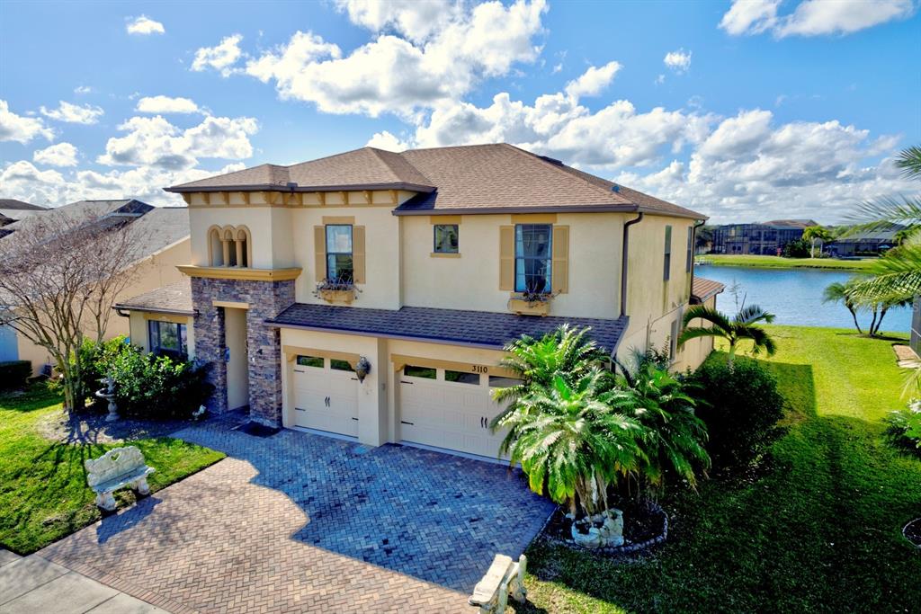 An aerial view of a two-story house with a stone facade, garage, and brick driveway — 3110 BASS BOAT WAY, KISSIMMEE, FL