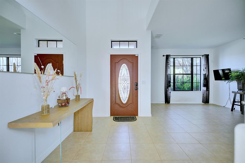 A bright entryway features a wooden console table, tile flooring, and a front door — 3110 BASS BOAT WAY, KISSIMMEE, FL