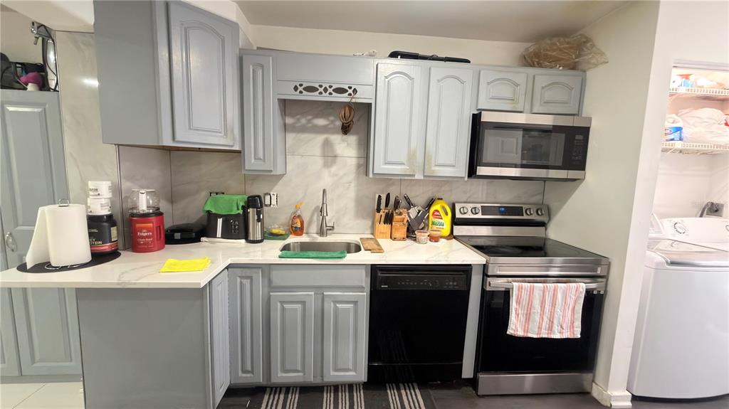 A kitchen features light blue cabinets, stainless steel appliances, and white countertops with a backsplash — 5304 INDIAN CREEK DRIVE UNIT D03, ORLANDO, FL