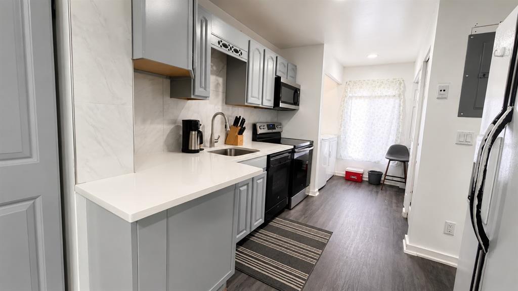 A kitchen features light gray cabinets, white countertops, black appliances, and dark wood-look flooring — 5304 INDIAN CREEK DRIVE UNIT D03, ORLANDO, FL
