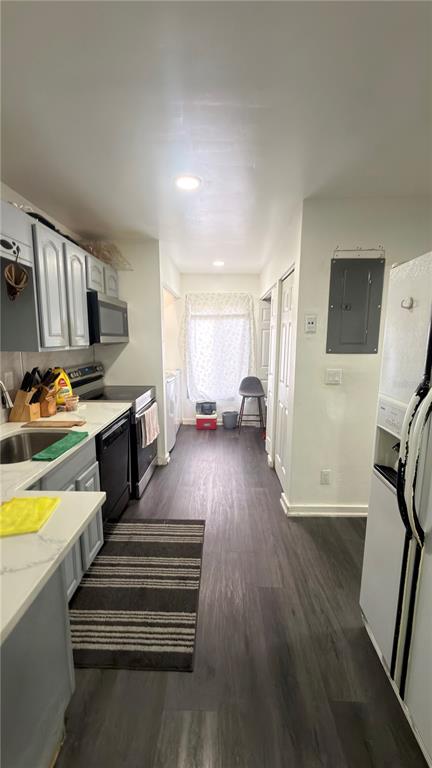 A narrow kitchen features light gray cabinets, dark wood-look flooring, and a window at the end — 5304 INDIAN CREEK DRIVE UNIT D03, ORLANDO, FL