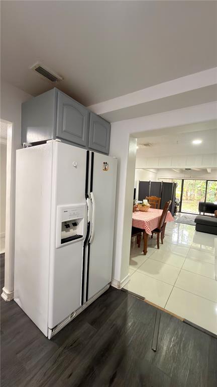 A white side-by-side refrigerator sits next to a dining area with tiled floors — 5304 INDIAN CREEK DRIVE UNIT D03, ORLANDO, FL