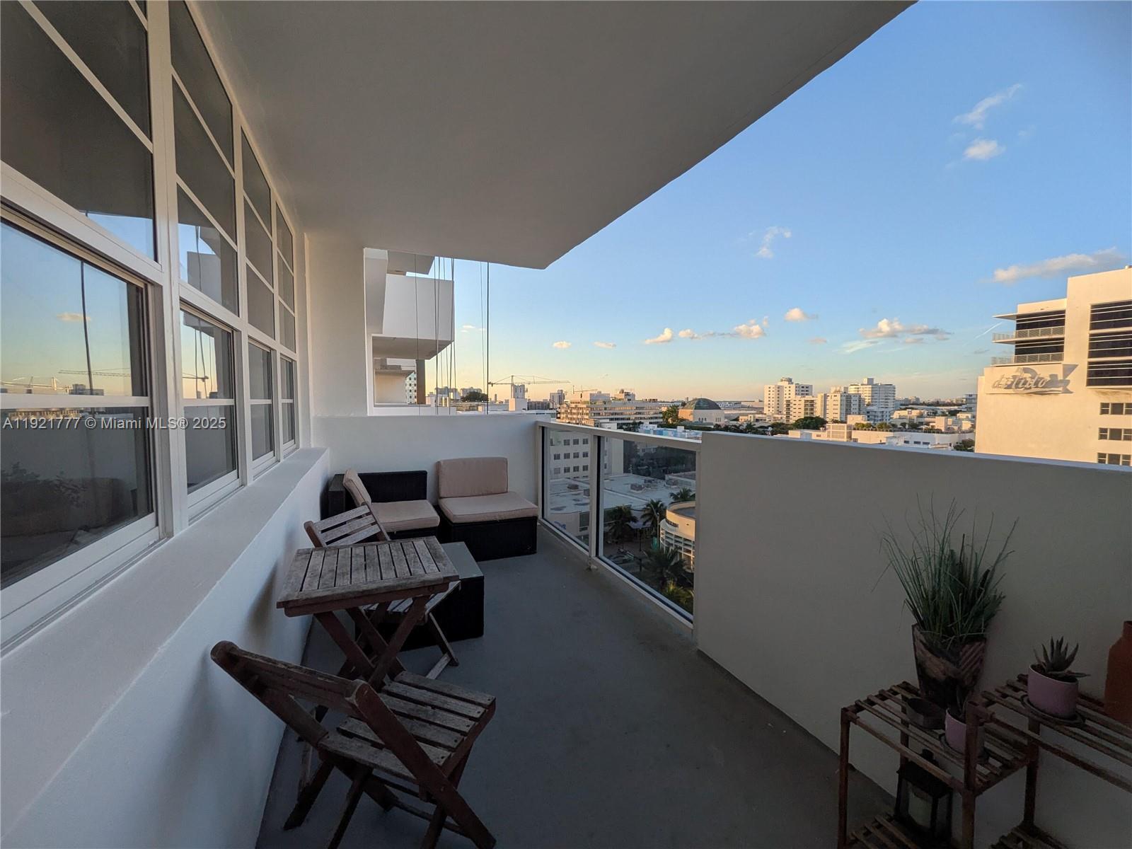 A balcony features a small wooden table, folding chairs, outdoor seating, and city skyline views — 100 Lincoln Rd # 904, Miami Beach FL 33139, MIAMI BEACH, FL