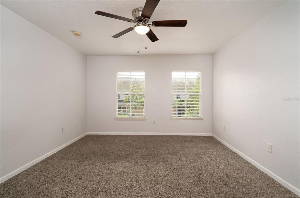 A bedroom with gray carpet, white walls, two windows, and a ceiling fan — 7818 BALLY MONEY ROAD, TAMPA, FL