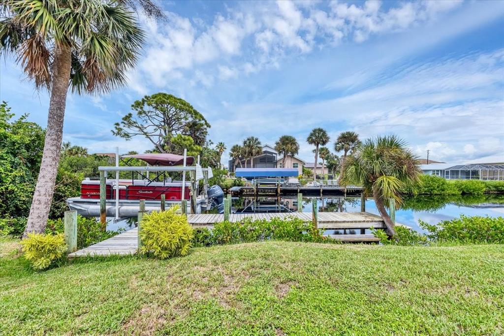 A wooden dock with two boat lifts sits on a canal surrounded by palm trees — 4696 POMPANO STREET, PLACIDA, FL