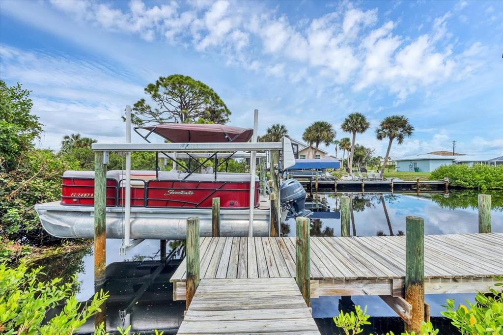 A red pontoon boat sits on a lift next to a wooden dock — 4696 POMPANO STREET, PLACIDA, FL