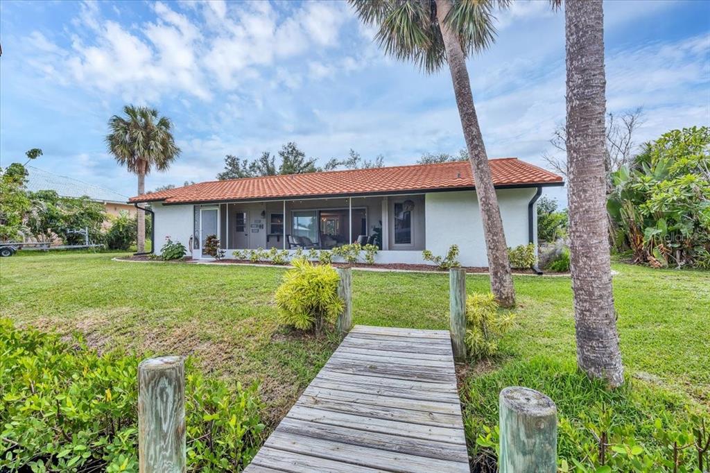 A single-story house with a red tile roof sits behind a wooden dock — 4696 POMPANO STREET, PLACIDA, FL