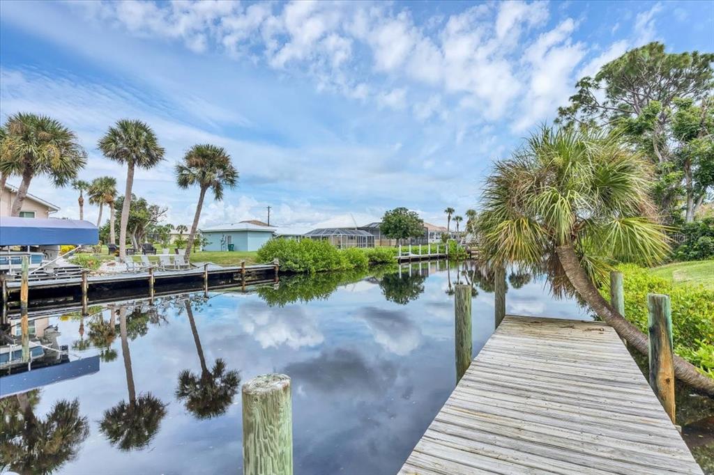 A wooden dock extends into a canal lined with palm trees and residential properties — 4696 POMPANO STREET, PLACIDA, FL