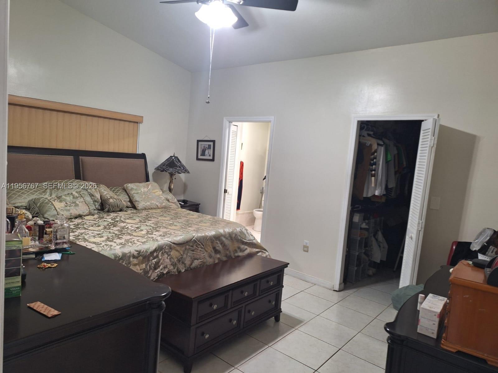 A bedroom features a bed, a storage bench, a walk-in closet, and an attached bathroom — 13822 SW 156th St, Miami FL 33177, MIAMI, FL